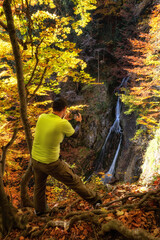 Wall Mural - Hiker and waterfall called Klacky vodopad in autumn forest ar Little Fatra mountains in Slovakia