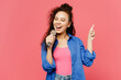 © ViDi Studio - Young expressive woman of African American ethnicity she wear blue shirt casual clothes sing song in microphone point index finger up isolated on plain pastel pink background studio Lifestyle concept