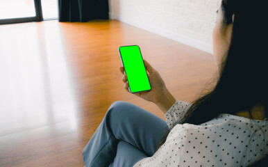 Poster - Mockup image, asian woman holding black smartphone with blank green screen at home or office