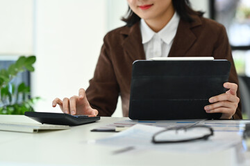 Wall Mural - Female accountant or banker using digital tablet, summarizing taxes or bills at workplace.