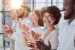 © Katsiaryna - Group of businesspeople sitting in a line and applauding.