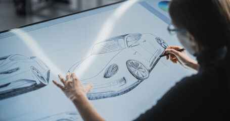 Wall Mural - Female Car Designer Using a Digital Tablet to Draw a Prototype Car Sketch with a Stylus. Talented Industrial Artist Working in a Research and Development Studio at a Vehicle Production Factory