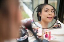 Close-up Image Of A Beautiful Asian Woman Looking At The Mirror While Applying Makeup In Her Room
