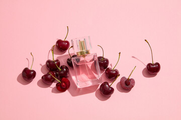 Wall Mural - Mockup scene for advertising product. A glass perfume bottle displayed on a pink background with fresh ripe cherries. The scent of cherry as a perfume oil is very popular with women