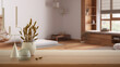 Wooden table, desk or shelf close up with ceramic and glass vases with dry plants, straws over blurred view of minimalist bathroom with ceramic bathtub, modern interior design concept