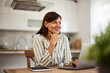 © bnenin - A happy female freelancer sitting in front of a laptop at the home office.