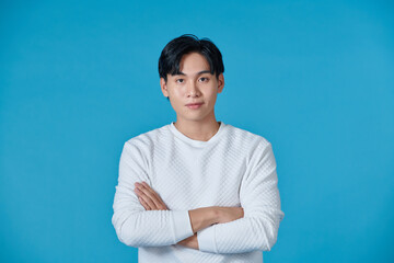 Wall Mural - Young asian man posing on a blue background