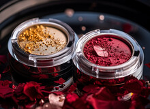 A Close-up Of Pearlescent Shimmery Palette Of Red And Orange Glitter Eyeshadows For Creating Eye Makeup