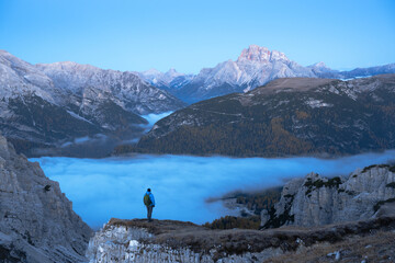 Wall Mural - A tourist stands over the fog at the edge of a cliff in the Dolomites mountains. Location Auronzo rifugio in Tre Cime di Lavaredo National Park, Dolomites, Trentino Alto Adige, Italy