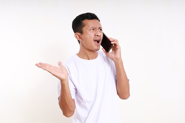 Wall Mural - Angry asian funny man standing while on phone. Isolated on white background