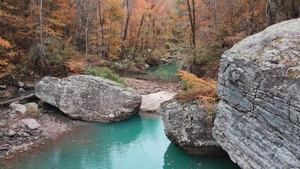 Wall Mural - Backward moving aerial of beautiful brook with blue water and large boulders in Ozark Mountains during autumn 