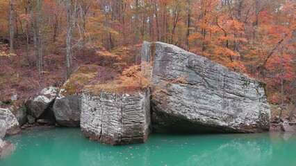 Wall Mural - Drone reveal of beautiful pool of water and large boulders in Arkansas ozark mountain creek in fall forest with autumn colored leaves 
