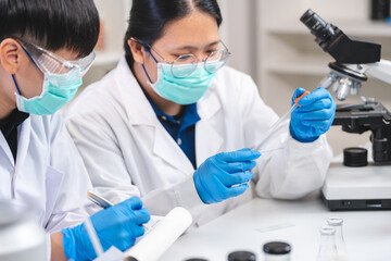 Wall Mural - Food scientist testing new stuff samples of dairy products in the laboratory, female laboratory assistant checks a quality of milk, bottles glassware and glasses of milk to testing lactose forms