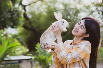 Wall Mural - relationships of cheerful rabbit and happy young human girl, Asian woman holding and carrying cute rabbit with tenderness and love. Friendship with cute easter bunny. Happy of Easter's Day