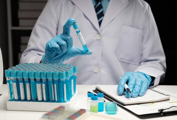 Wall Mural - Scientist hand taking a sample tube from a rack with machines of analysis in the lab background, Technician holding tube test in the research laboratory.