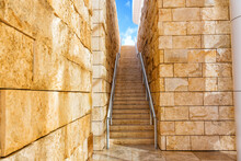 Ascending Steps In A Narrow Passage Leading To Blue Sky