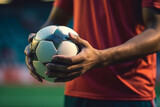 Fototapeta Sport - Soccer player holding soccer ball in hand with stadium background.