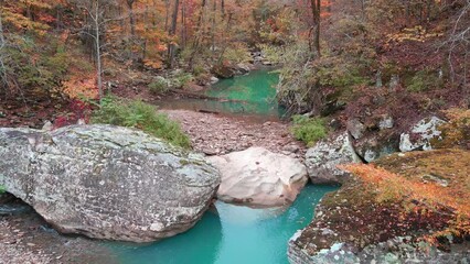 Wall Mural - Beautiful turquoise pool of water and large boulders in ozark mountain creek via aerial drone reverse perspective in autumn 