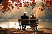 Senior Couple Sitting On A Bench In A Autumn Park, Back View. AI Generated