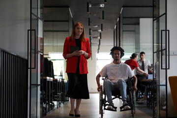 A group of young business people in a modern glass-walled office captures the essence of diversity and collaboration, while two colleagues, including an African American businessman in a wheelchair