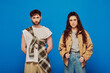 © LIGHTFIELD STUDIOS - stylish couple in casual wear on blue backdrop, woman and man looking at camera, fashionable