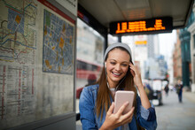 Young Caucasian Woman Using A Smart Phone While Waiting For A Bus At The Bus Stop In London UK