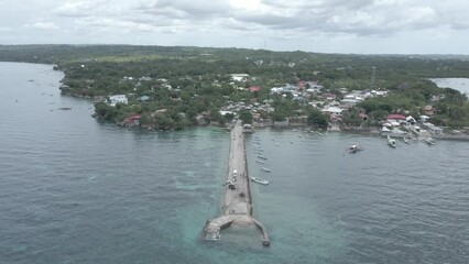 Sticker - Drone flying over an island with small houses and trees landscape, boats docked near the pier