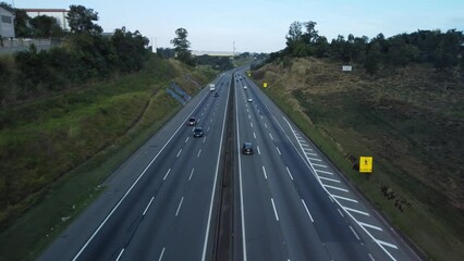 Wall Mural - Aerial footage of cars driving on lanes of highway road with trees and blue sky