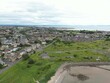 Aerial view of residential area with lush green grass and a bay in the background in Scotland