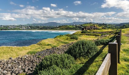 Sticker - Scenic lush green landscape with a wooden fence and a large body of water