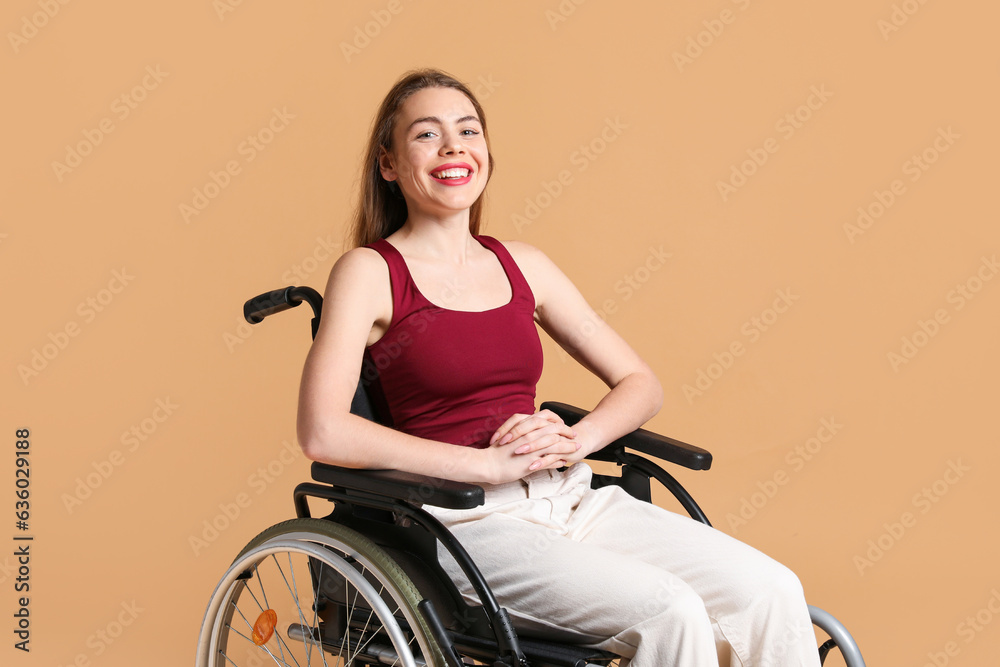Young woman in wheelchair on beige background