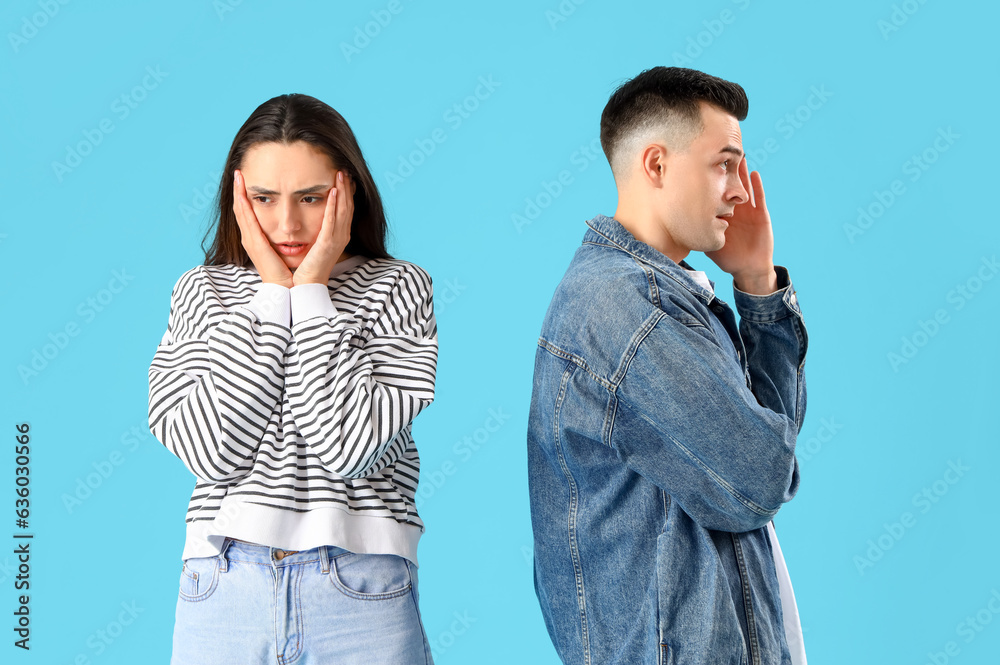 Offended young couple after quarrel on blue background
