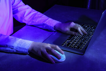 Female programmer working with laptop keyboard at night in office, closeup