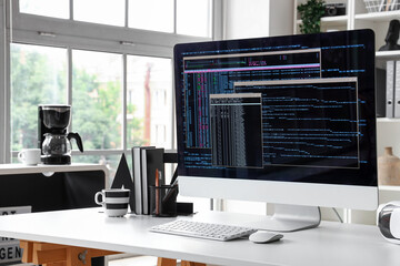 Computer monitor with programming code at workplace in office