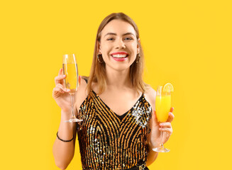 Wall Mural - Beautiful young woman with different cocktails on yellow background