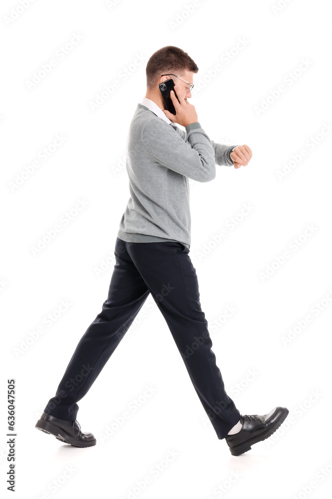 Businessman talking by phone and checking time while walking away on white background