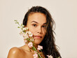 © ohlamour studio/Stocksy - Woman with wet hair and bouquet of flowers, beauty studio portrait