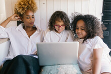 Mother With Her Two Daughters Using The Computer