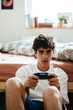 © BONNINSTUDIO/Stocksy - Man playing video game on bedroom