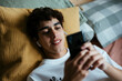 © BONNINSTUDIO/Stocksy - Teen boy using phone in bed