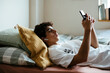 © BONNINSTUDIO/Stocksy - Teen boy using phone in bed