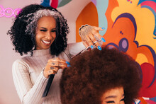 Cheerful Latin Hairdresser Cutting Afro Hair To A Client