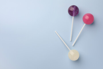 Tasty lollipops on light blue background, flat lay. Space for text