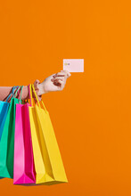Woman Hand With Shopping Bags And Credit Card On Orange Background