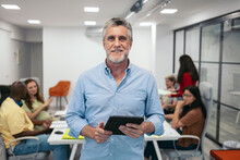 Portrait Of A Smiling Mature Man Holding A Tablet In The Office