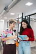 © Pedro Merino/Stocksy - Young coworkers standing reviewing a business plan on the tablet