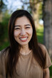 © Rob and Julia Campbell/Stocksy - Happily smiling woman in front of a tree, showing teeth.