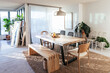© Sophia Hsin/Stocksy - Dining and living room with table plants, and hanging light pendant