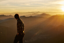 Man Backlit At Sunrise With Mountain Range In Background Lens Flare