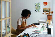 Curly Woman Painting In Bright Art Studio